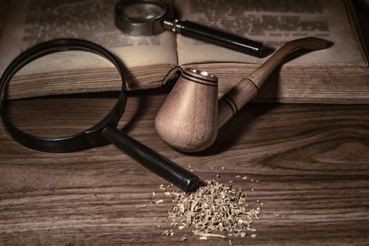 Smoking pipe with tobacco leaves on wooden background.wooden background.Wooden pipe with smoke on heap of chopped dried tobacco leaves against black background.