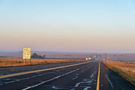 The sun is rising over road N1 at the Verkeerdevlei junction north of Bloemfontein, South Africa