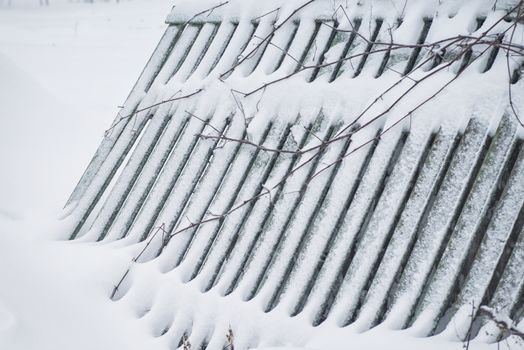 Winter landscape. Season winter. The wooden fence is noticeable with snow.