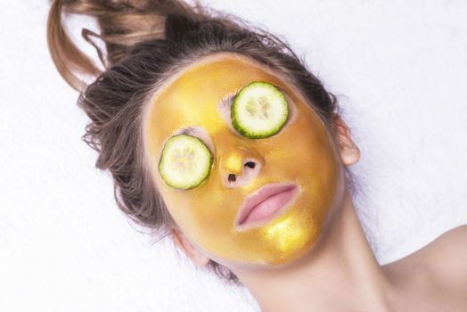 Beautiful girl with a cosmetic mask on the face of golden color. Beautiful model removing golden facial skin cosmetic. Beauty skincare .Close-up. Free space. Woman gold mask. .