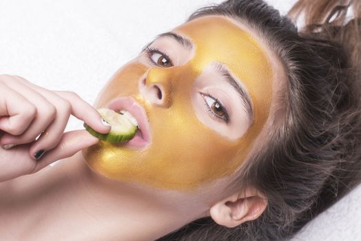 Beautiful girl with a cosmetic mask on the face of golden color. Beautiful model removing golden facial skin cosmetic. Beauty skincare .Close-up. Free space. Woman gold mask. .