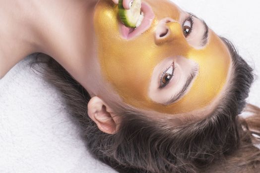 Beautiful girl with a cosmetic mask on the face of golden color. Beautiful model removing golden facial skin cosmetic. Beauty skincare .Close-up. Free space. Woman gold mask. .