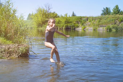 little girl running through the water with a splash . in her hands cloth.