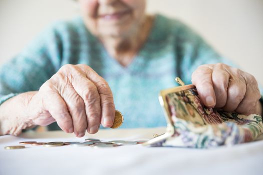 Detailed closeup photo of elderly 96 years old womans hands counting remaining coins from pension in her wallet after paying bills. Unsustainability of social transfers and pension system.