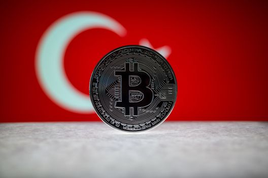 Physical silver version of Bitcoin (BTC) and Turkey Flag on the background. Conceptual image for investors in cryptocurrency and Blockchain Technology.