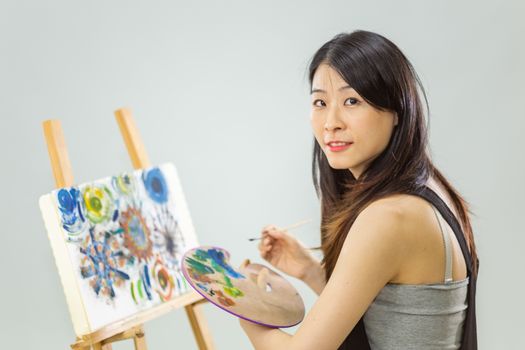 Artist painting on an easel, looking at camera