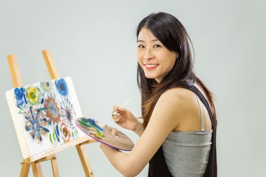 Artist painting on an easel, looking at camera