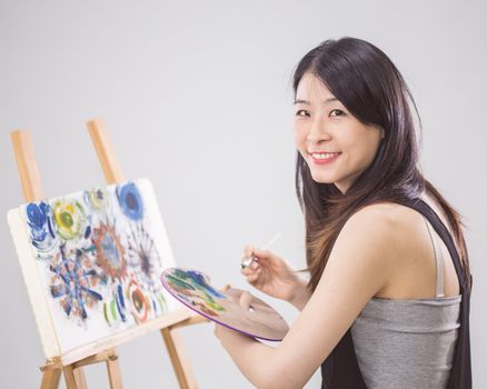 Artist painting on an easel, looking at camera