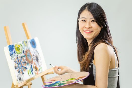 Artist painting on an easel, looking at camera