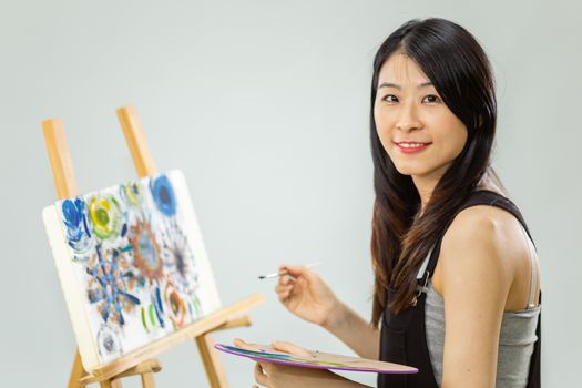 Artist painting on an easel, looking at camera