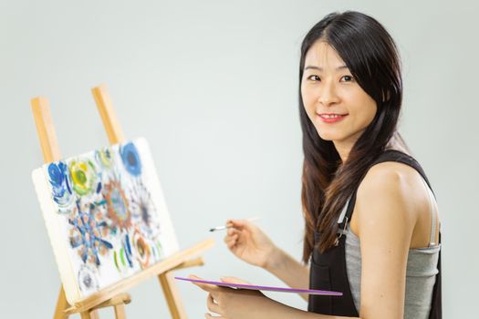 Artist painting on an easel, looking at camera