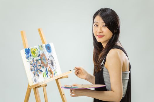 Artist painting on an easel, looking at camera