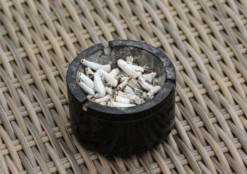 close up of ashtray filled with tobacco ash and cigarette butts