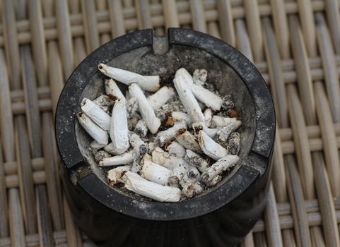 close up of ashtray filled with tobacco ash and cigarette butts