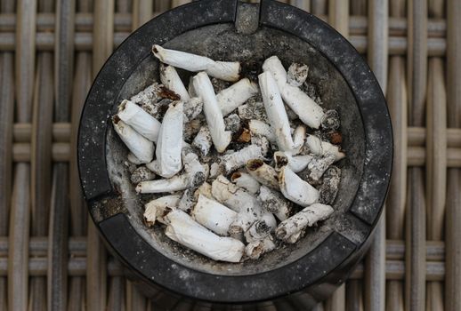 close up of ashtray filled with tobacco ash and cigarette butts