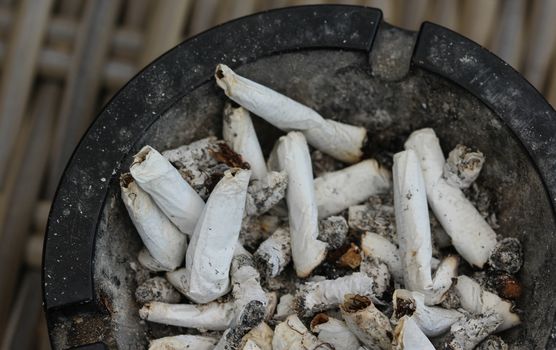 close up of ashtray filled with tobacco ash and cigarette butts