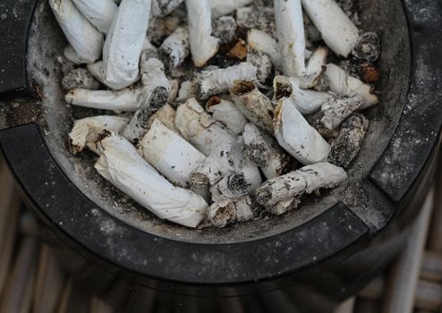 close up of ashtray filled with tobacco ash and cigarette butts