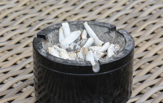 close up of ashtray filled with tobacco ash and cigarette butts