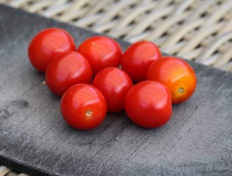 Close up of Fresh red cherry tomato on black cutting board background