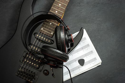 Black electric guitar and Headphone on black cement floor. Top view and copy space for text. Concept of rock music.