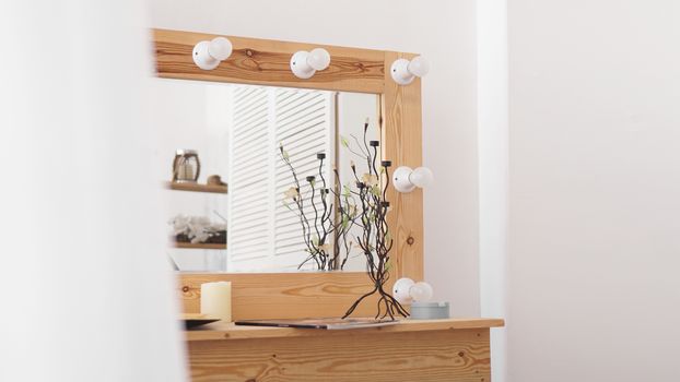 Table with makeup products and mirror near white wall. Dressing room interior. Modern interior in the girls bedroom