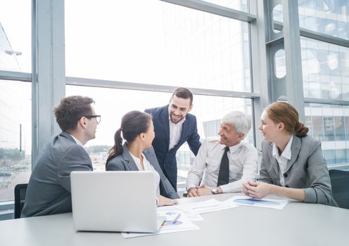 Business team sitting by the table with laptop and documents in office