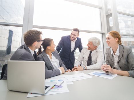 Business team sitting by the table with laptop and documents in office