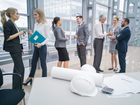 Business people team discuss construction issues , hardhat , blueprint , contract , documents , calculator on office table