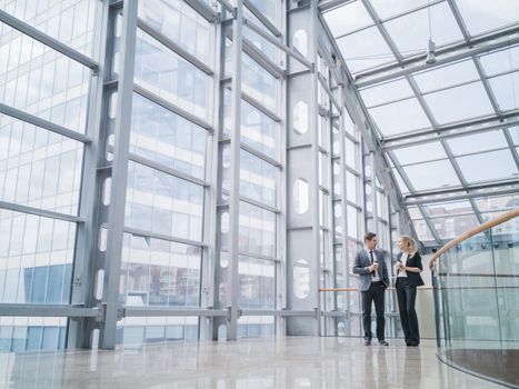 Businessman and businesswoman walk together and talk about business holding coffee in hand