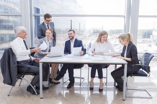 Business team sitting by the table with laptop and documents in office