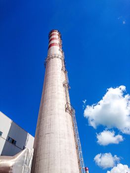 Brick factory pipe on a background of blue sky with white clouds. Bottom view. The concept of cleaner production.