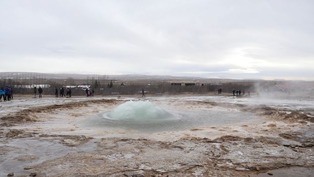 Geyser erupting in Iceland, producing big splash of hot water and steam