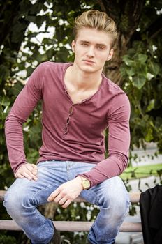 Handsome blond young man outdoors, looking away to a side