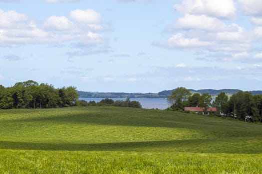 A hilly landscape in fredensborg denmark with a lake in the background