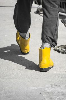 Fisherman is walking in the ports inyellow wellington boots, gum boots ampng ropes on a sumer day in Greece
