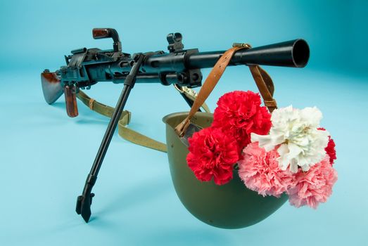 Machine gun and flowers in an army helmet