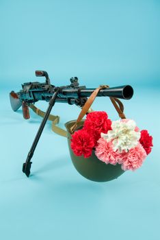 Machine gun and flowers in an army helmet