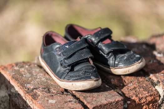 One pair of lost, abandoned kid shoes can symbol some missing child, one pair of kid shoes on a brick wall