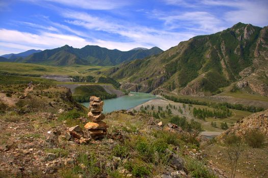 Sacral cairn on top of a hill overlooking the mountains and the river. Katun, Altai, Siberia, Russia.