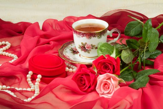 Cup of tea and bouquet of roses on a fabric background