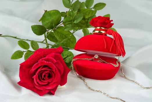 Ring in a box and red rose on a fabric background