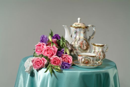 Tea set and bouquet of flowers on a studio background