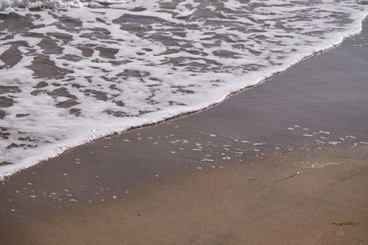 Sea waves on shoreline on orange sand