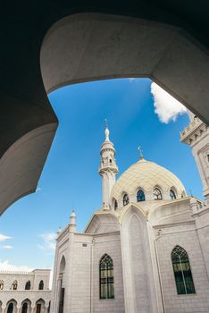 Beautiful White Mosque with Dome and Minaret. View through the Arch. Bolghar, Russia.