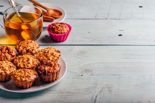 Healthy Dessert. Oatmeal muffins with cup of green tea over light wooden background. Copy Space.