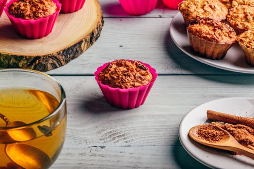 Healthy Dessert. Oatmeal muffins with cup of green tea over light wooden background.