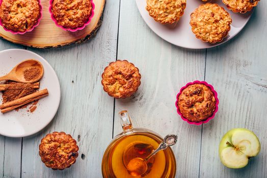 Healthy Breakfast. Cooked oatmeal muffins with apple and cup of green tea over light wooden background. View from above.