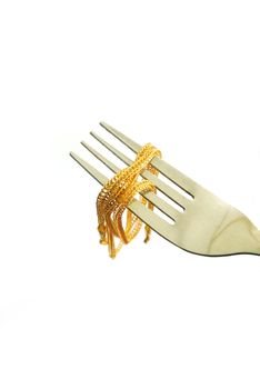 The gold neck weighs about 0.5 grams on the cutlery on white background.