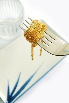 The gold neck weighs about 0.5 grams on the cutlery on white background.
