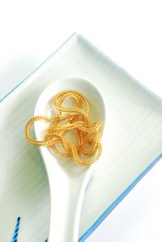 The gold neck weighs about 0.5 grams on a spoon on white background.